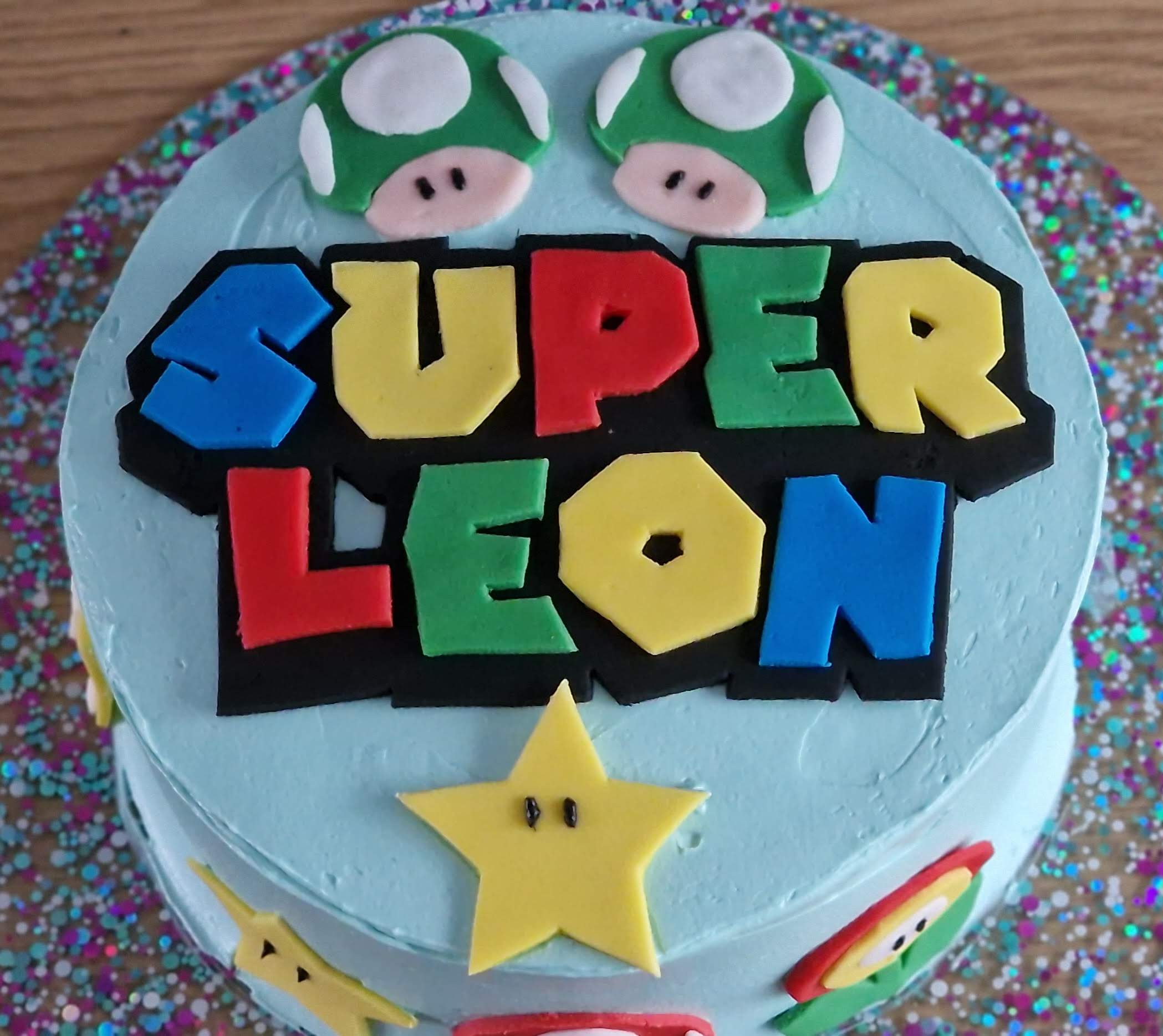 Bespoke lemon cake with vibrant blue frosting and customized Super Mario themed design elements for Leon, crafted by Fontaines Fancies