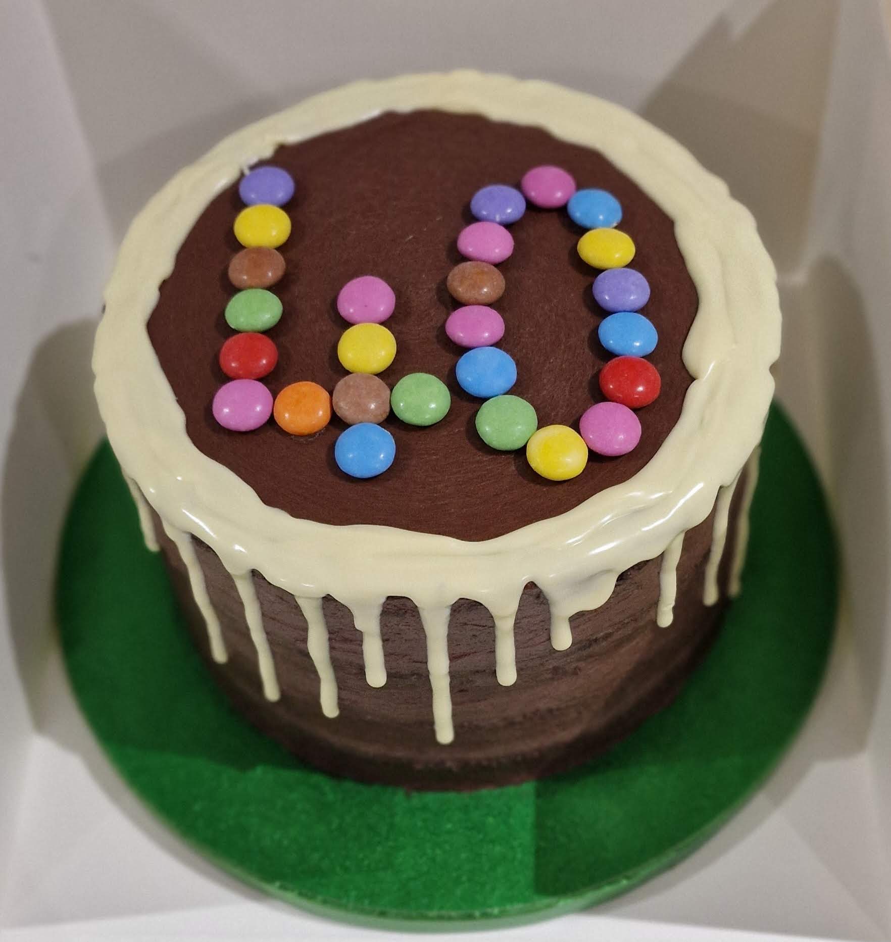 Custom chocolate cake with white chocolate drip decorated with colorful candies forming the number 40 for a birthday celebration by Fontaines Fancies in Perivale
